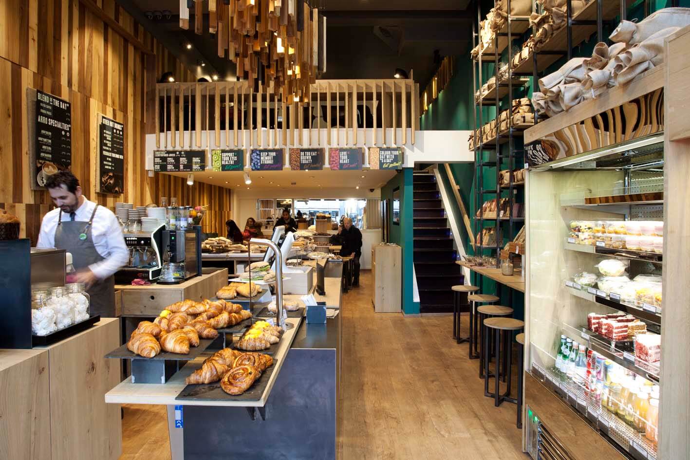 Interior of a bakery with a stocked fridge shelves on the right and fresh baked goods at the counter on the left.